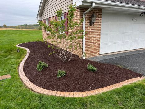 Decorative stone landscape border with fresh mulch beside garage