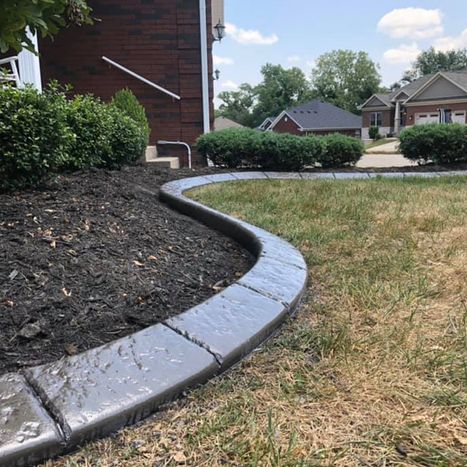 Smooth black stone landscape border separating mulch and lawn