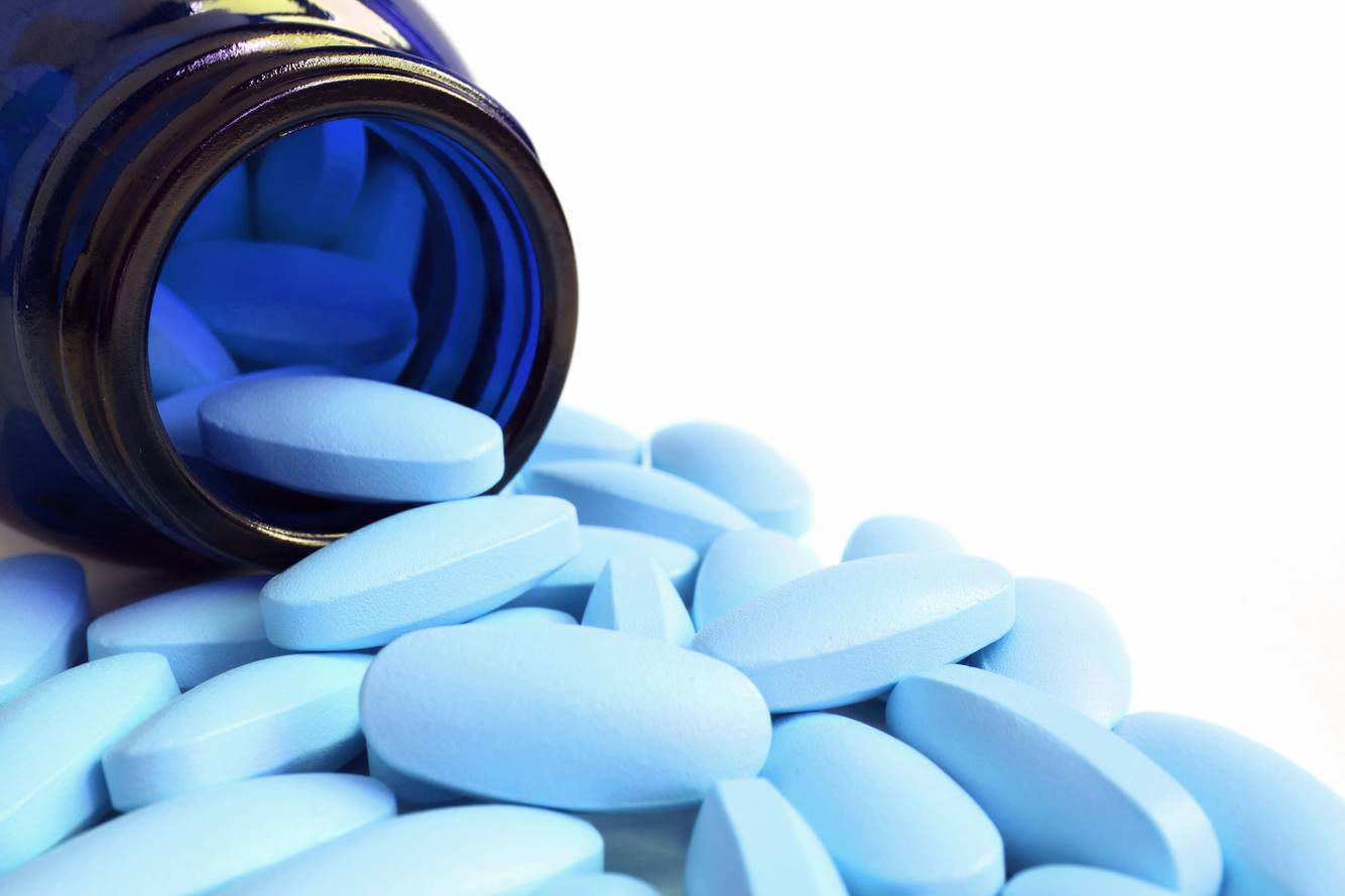 Pills spilling out of a blue bottle Medication Compliance