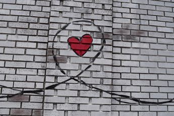 white brick wall with a red heart painted on it