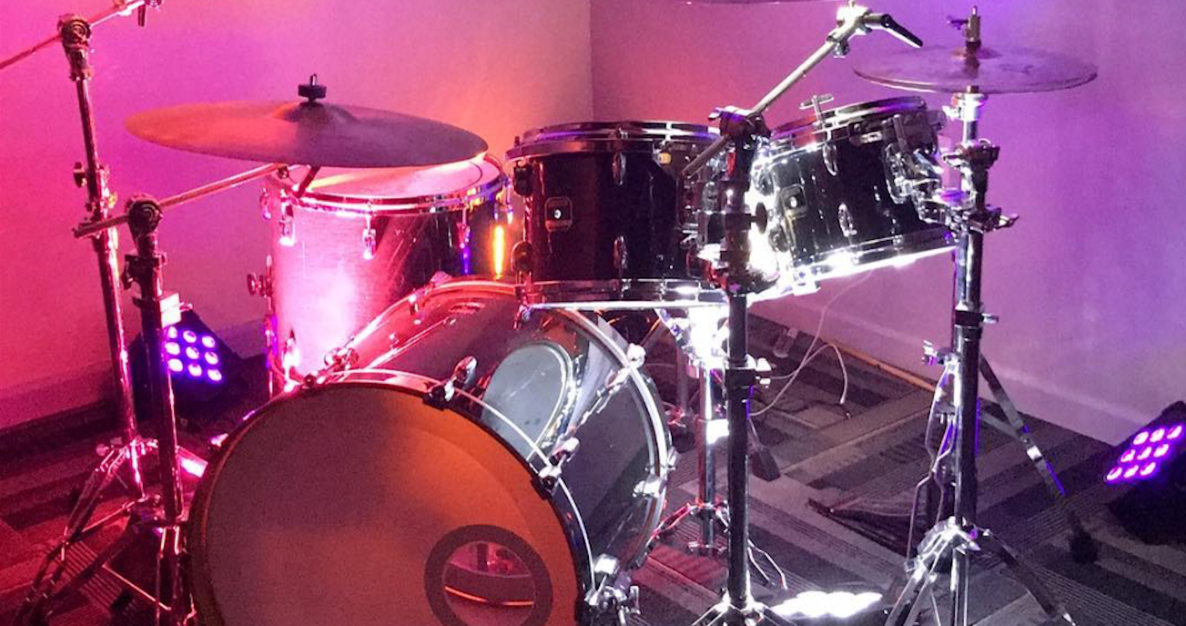 Close up of drum kit with pink lighting