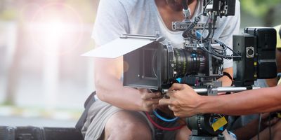 Two video technicians holding a camera at an outdoor event 