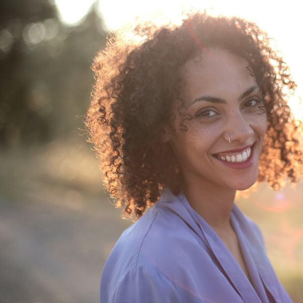 sun-shining-woman-with-curly-hair-surrounded-by-trees-grass.jpg