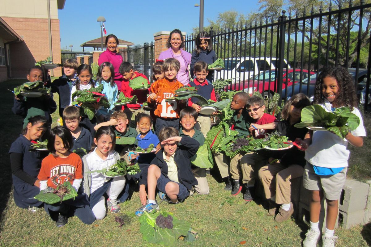 childlren posing with teacher and harvest from their school garden