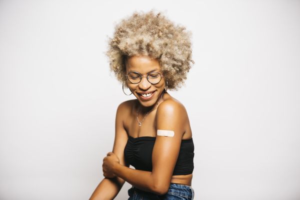 Woman with a bandaid on her upper arm. Travel Vaccines