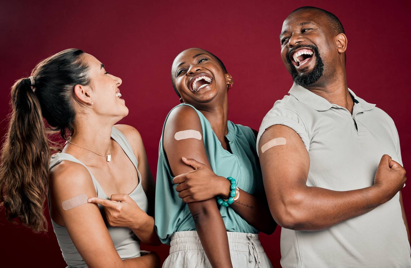 Group of people laughing together with bandaids on their upper arm Immunizations
