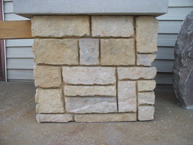 Stone flagpole base with natural boulder texture by Boulder Designs