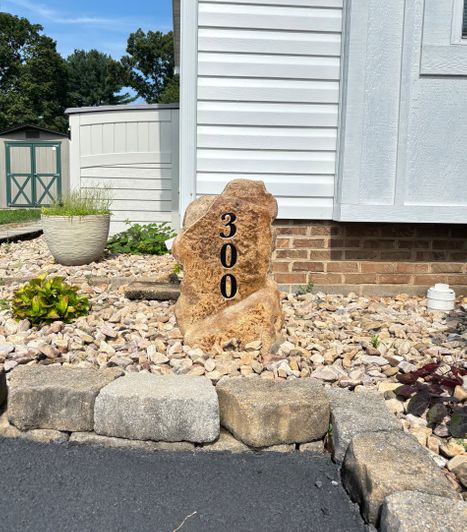 Vertical landscape stone house number marker engraved with 300, installed in decorative rock beside a home exterior located in Bridgewater, VA, created by Angelopulos StoneCraft.