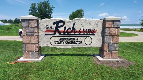Etched and engraved rock and boulder business monument sign between stone columns