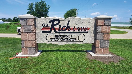 Etched and engraved rock and boulder business monument sign between stone columns