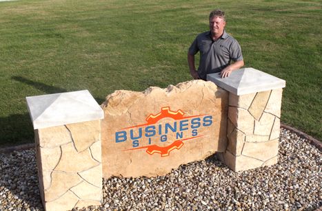 Etched and engraved stone business sign with decorative stone columns