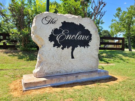 Engraved Enclave neighborhood boulder sign featuring tree graphic