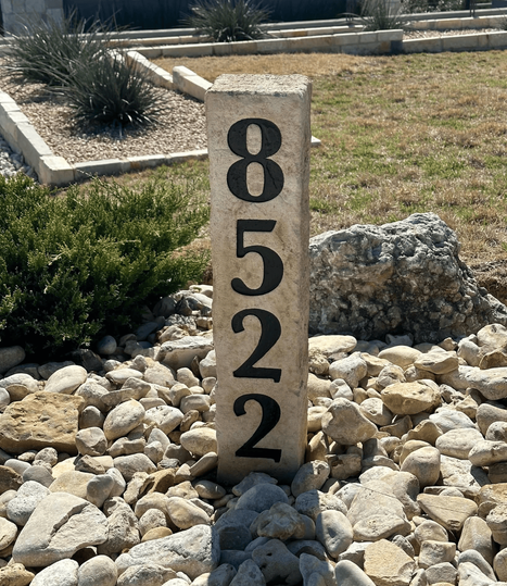 Tall vertical address boulder post engraved with the numbers 8522, set in decorative landscape rocks and greenery, created by Boulder Designs.