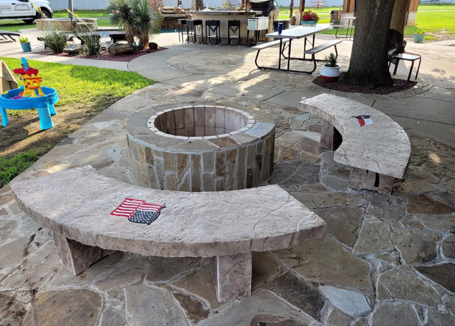 Boulder-style fire pit with curved stone benches by Boulder Designs