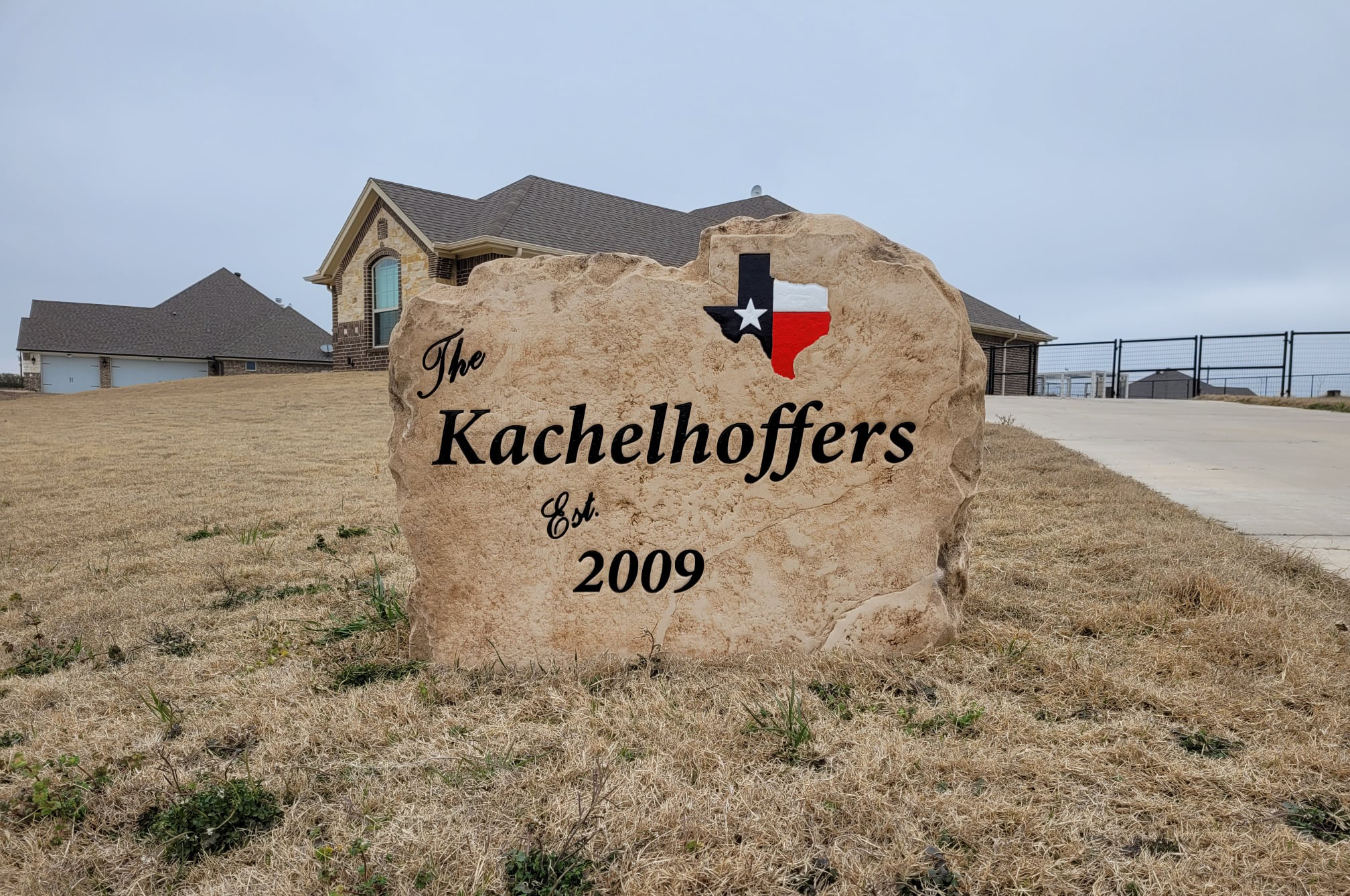Custom engraved stone family sign with Texas emblem in front yard