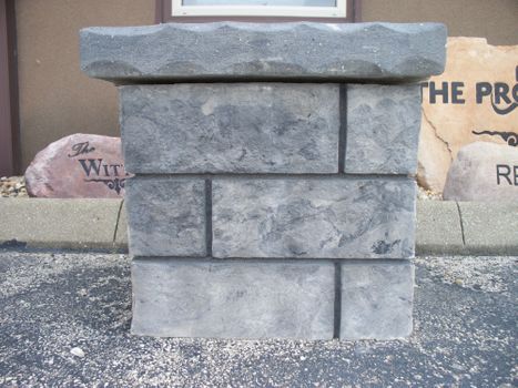 Gray stone flagpole base with natural boulder texture by Boulder Designs