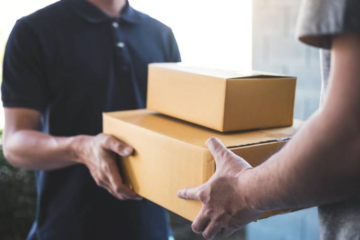 A delivery driver handing two packages to a person Free Delivery