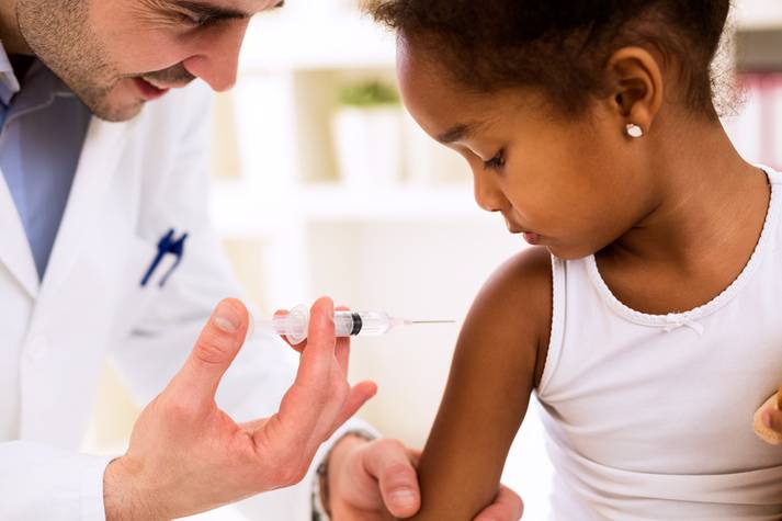 A pharmacist giving a young girl a shot Immunizations