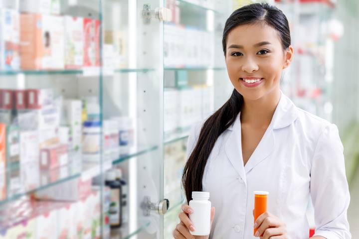 We provide consultations to avoid non-adherence. Image of pharmacist smiling and holding pills