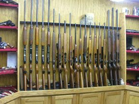 A series of long guns standing up on a gun rack.