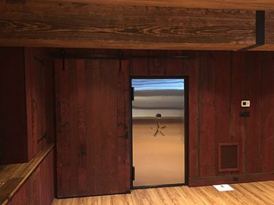 Silver vault door installed against a wooden wall.