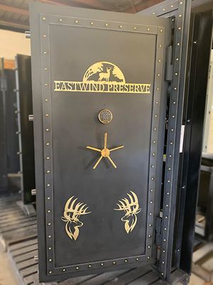 This custom Steampunk vault door has brass rivets and cut outs with custom text, Eastwind Preserve with two pictures of deer at the bottom.