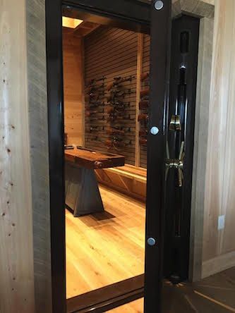 an installed vault door cracked open to show the inside of a vault room that contains many different guns mounted on the wall. an installed vault door cracked open to show the inside of a vault room that contains many different guns mounted on the wall.