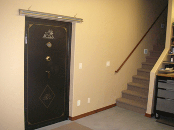 A vault room door installed in a wall next to a staircase.