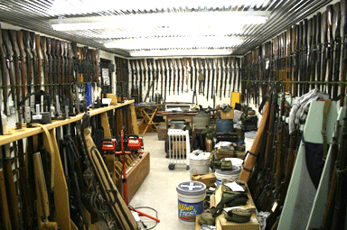 A vault room containing different guns and survival gear against the walls.