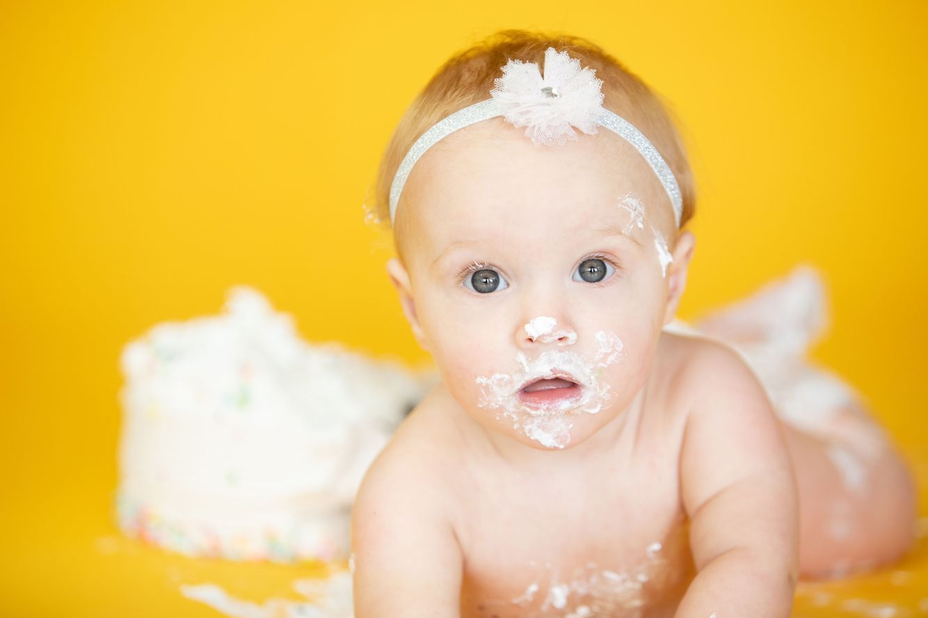 Baby laying on her tummy after eating cake from her 1 Year Cake Smash Session at our Denver Studio.