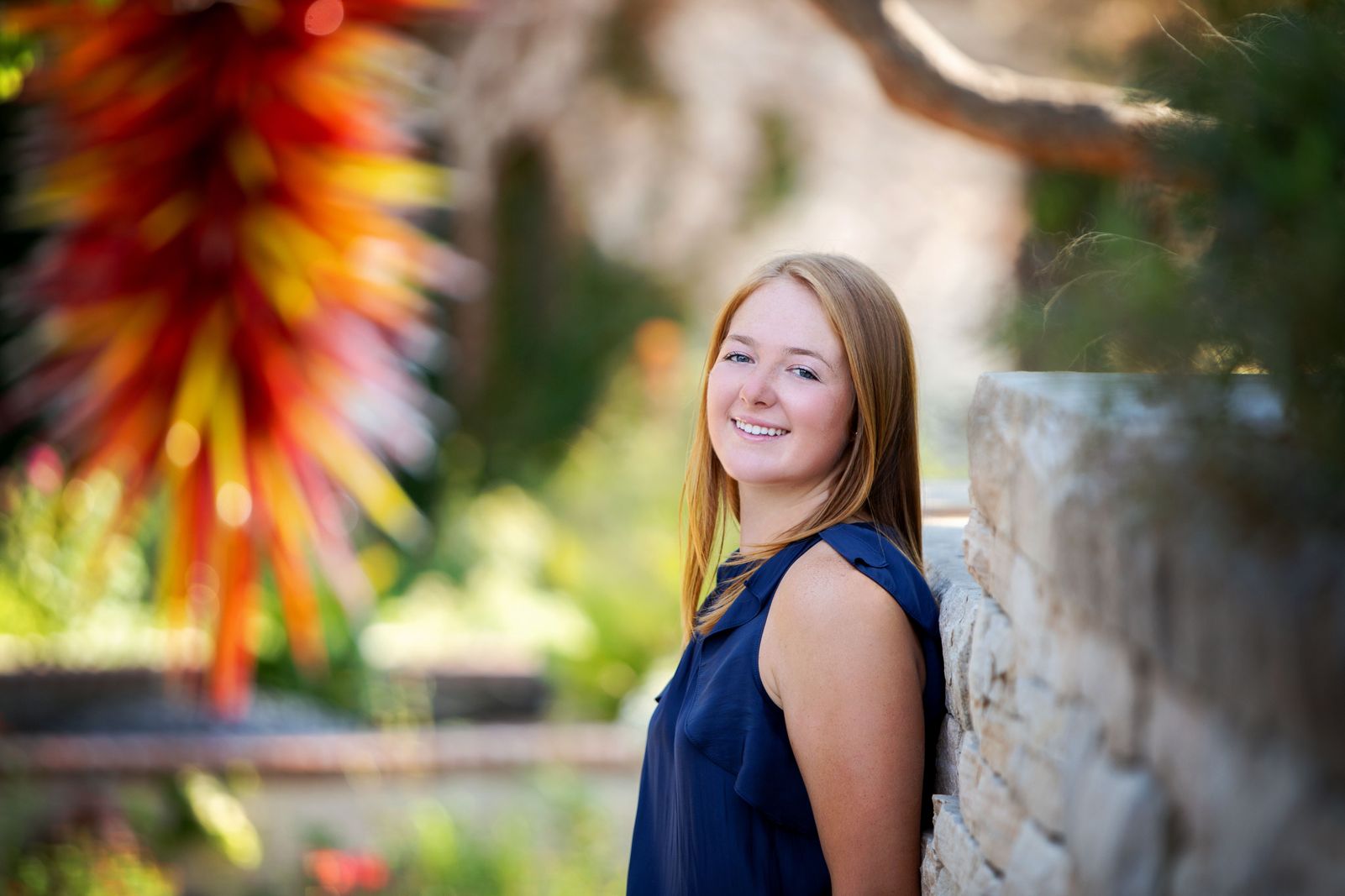 High School Senior girl posing for a picture in front of a Chihuly sculpture at the Denver Botanic Gardens. 