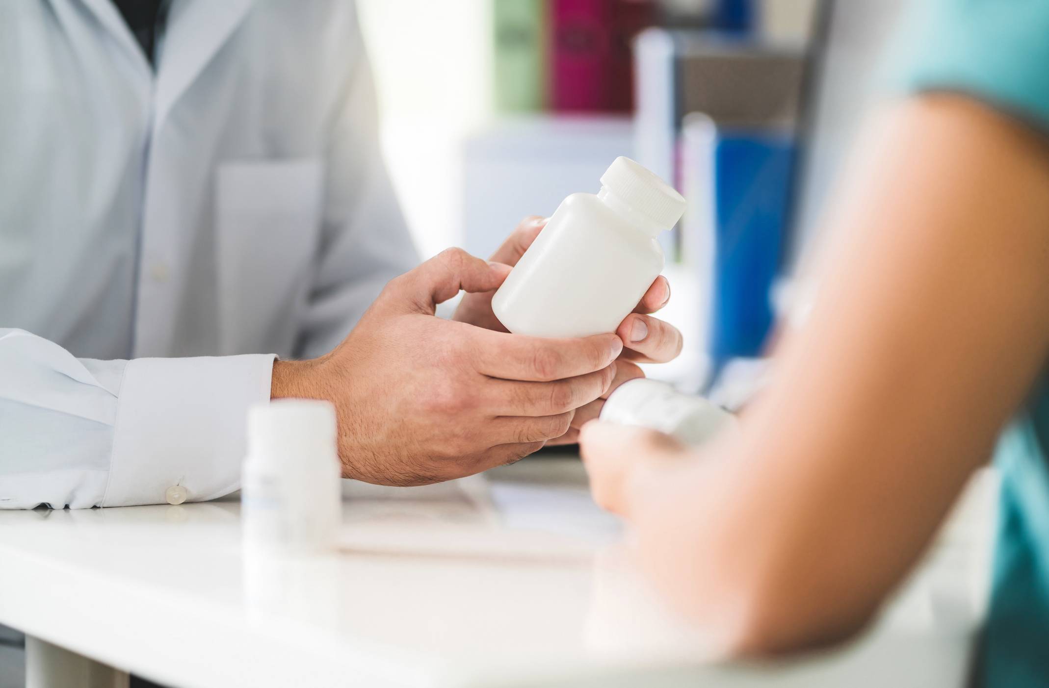 A pharmacist holding medicine and talking to a patient Medication Adherence