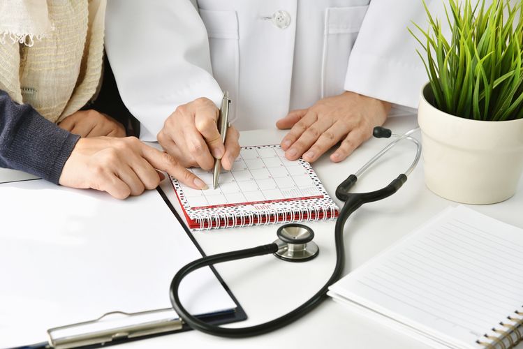 Pharmacist and patient marking a date on a calendar Health Screenings