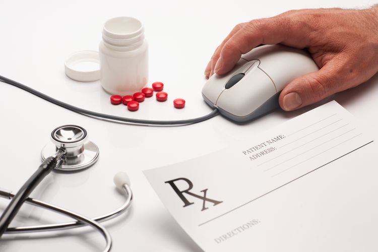 Person using a mouse next to a prescription and medicine Curbside Pickup