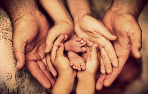 Family hands holding the feet of a newborn