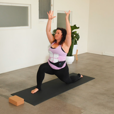 Woman doing yoga in pink tank top and black leggings.png