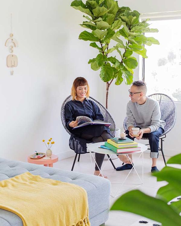 Two people sitting in chairs and talking in a room with lots of plants 5