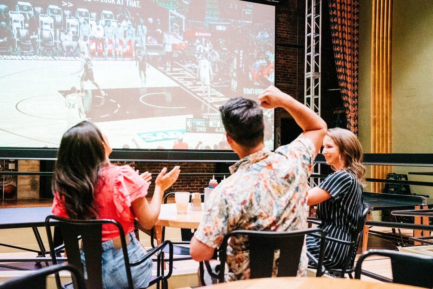 Guests watching a live sports game at Mainzer's Theater | Restaurant, Music Venue, and Movie Theater Guests at Mainzer's Theater | Restaurant, Music Venue, and Movie Theater