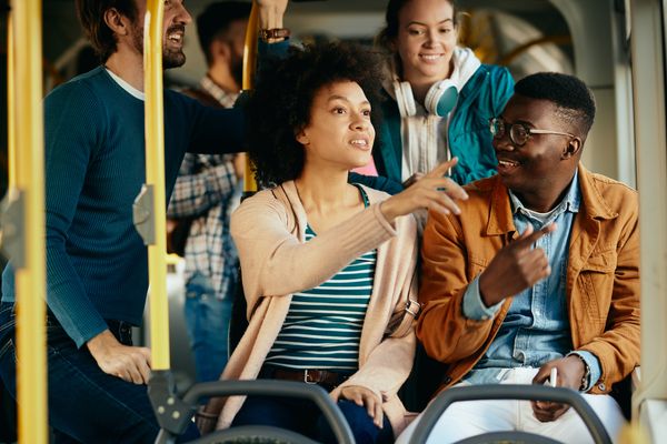 happy-black-couple-talking-pointing-through-window-while-commuting-by-bus.jpg