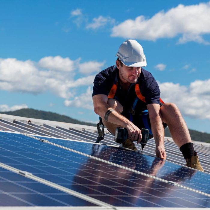 a worker on a roof drilling in solar panels