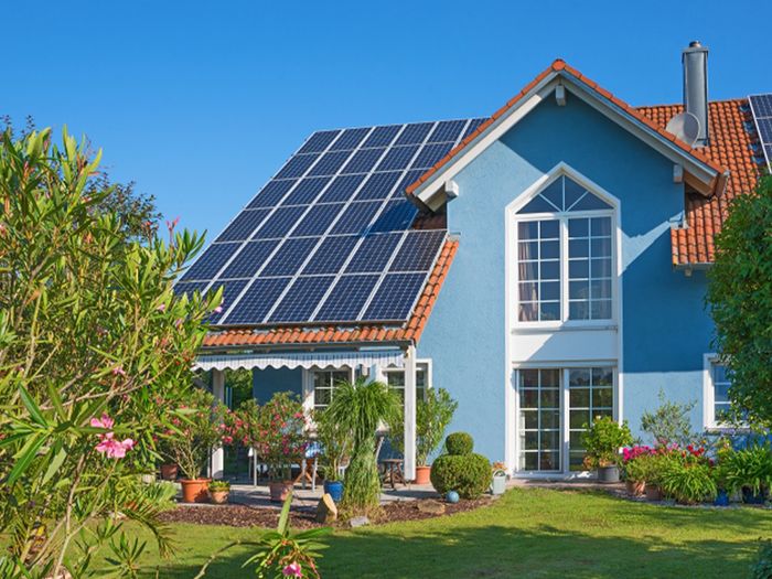 Image of luxury home with nice landscaping and solar panels mounted on roof