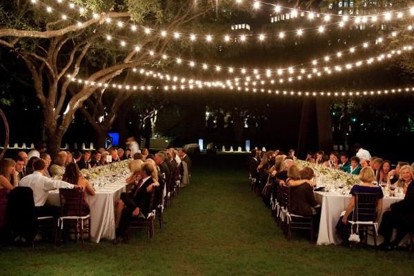 Guests seated under string lights at an outdoor wedding reception