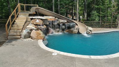 hand crafted rock waterfeature with pool slide glass tile