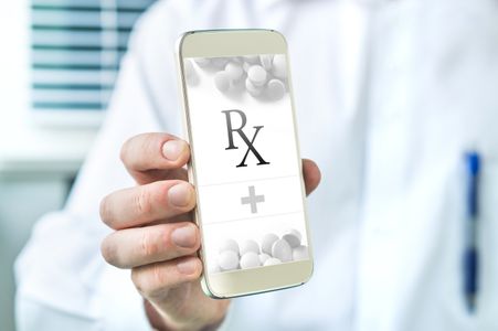 Pharmacist holding a phone with RX on it Text Notifications