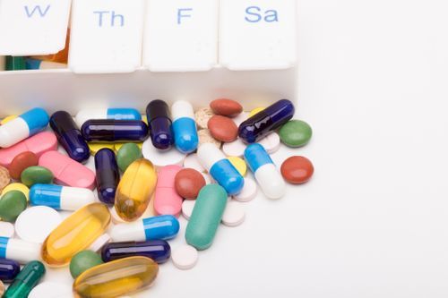 Image of medication spilled in front of a pill organizer Medication Adherence