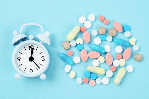 Spilled pills next to an alarm clock Med Sync