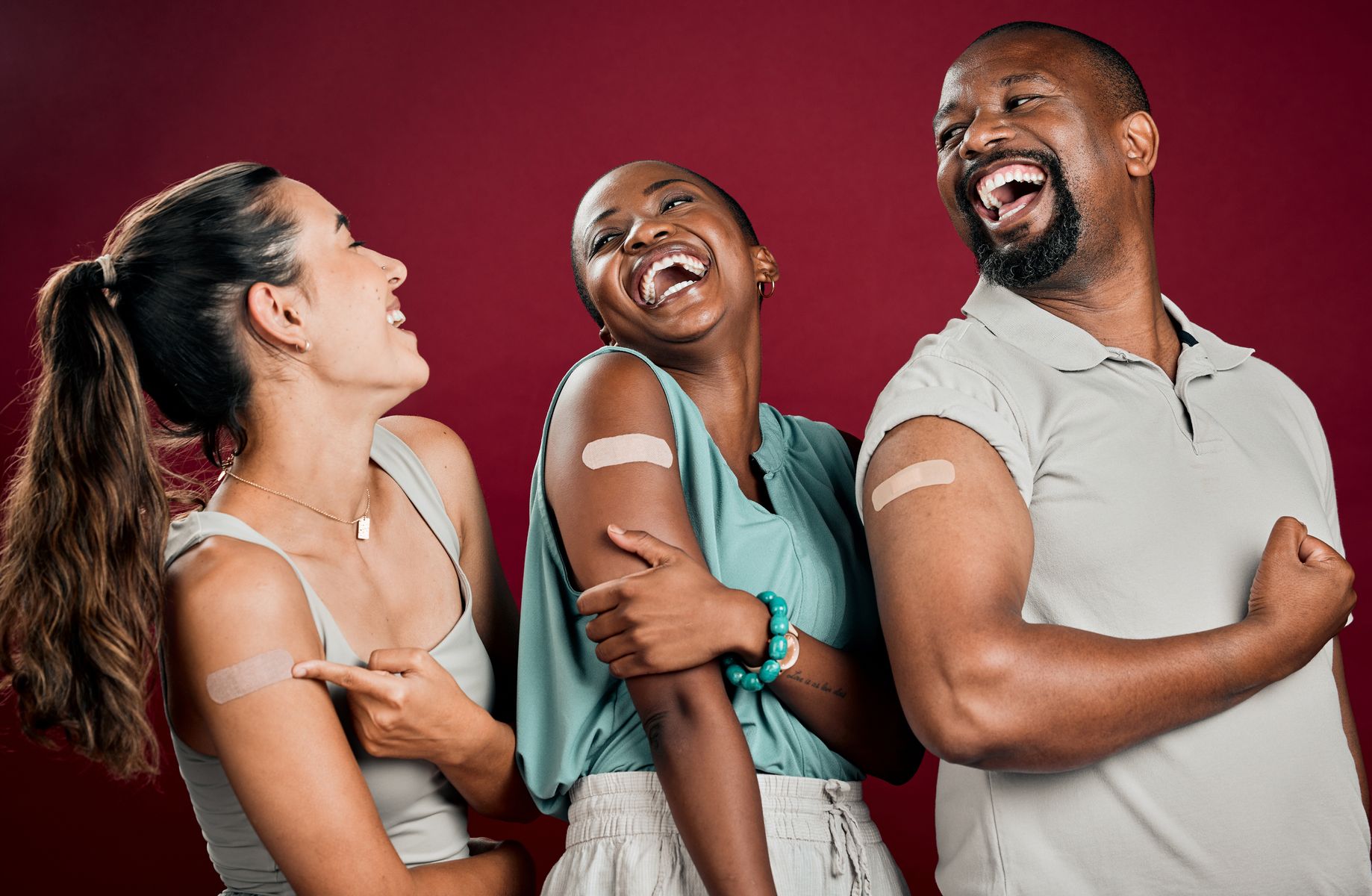 People laughing together with bandaids on their upper arm. Vaccines