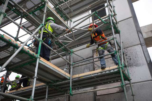 Restoration workers on scaffolding performing commercial structural repair at a building site