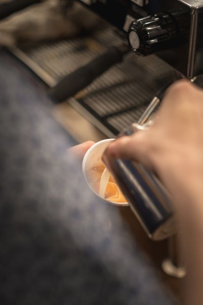 barista pours milk into a to go cup latte being poured in dashery