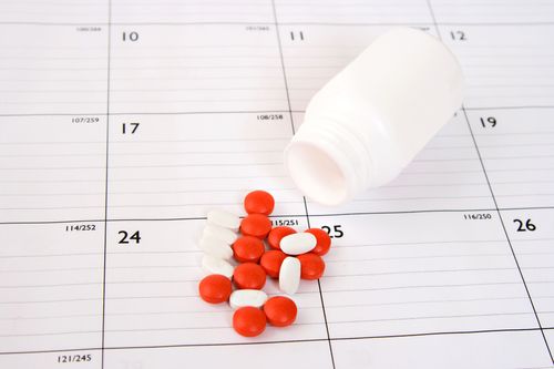 Bottle of prescription pills spilled out onto a paper calendar
